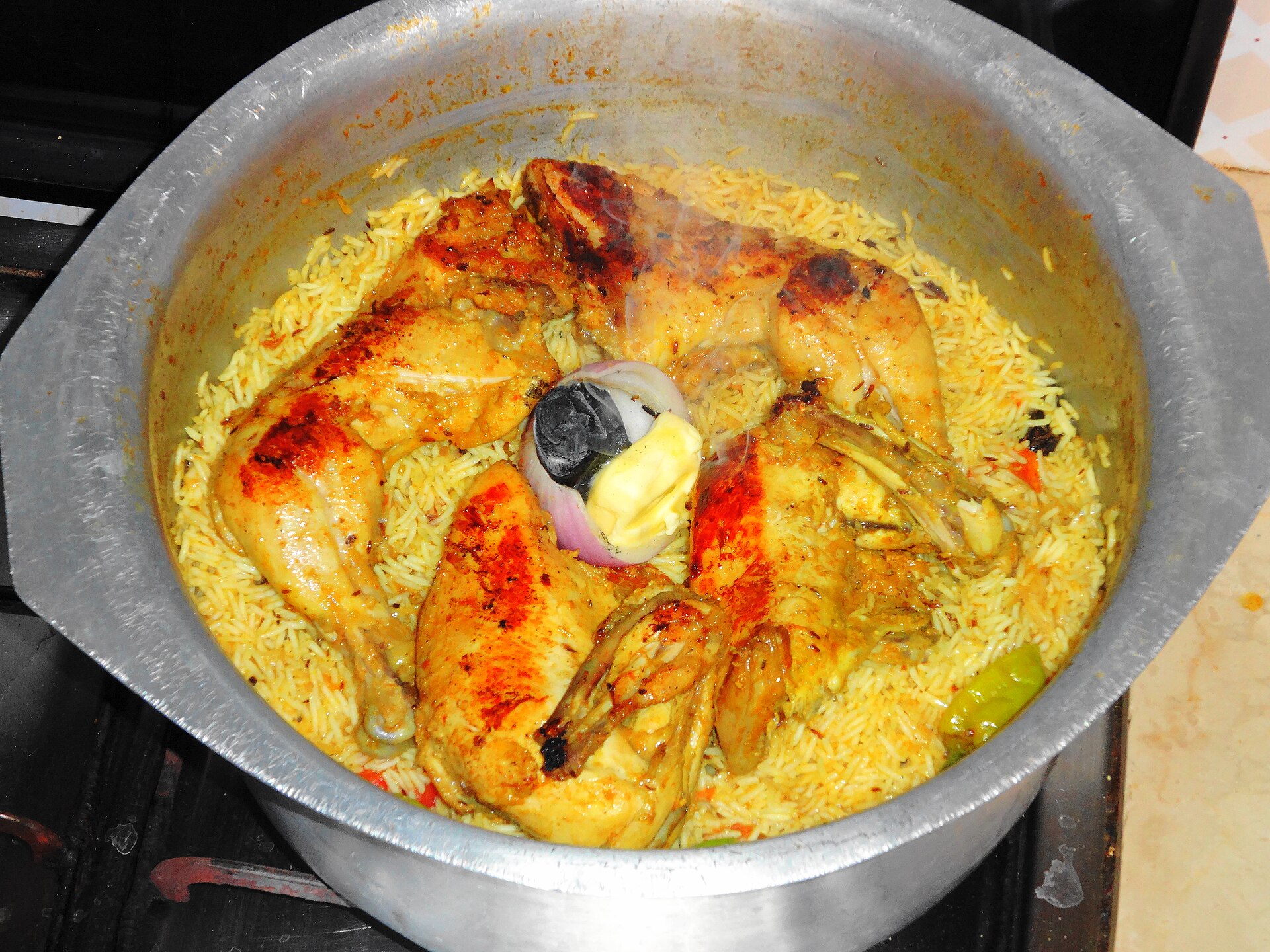 Traditional chicken mandi rice being prepared over charcoal — a classic Saudi Arabian dish
