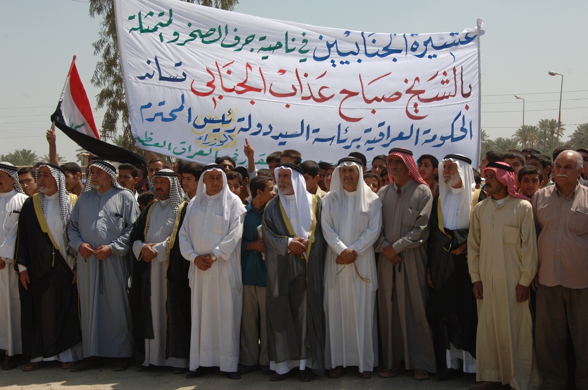 Residents of Jurf as Sakhr, Iraq, holding a banner during a local demonstration. Jurf al-Sakhr is a Kata ib Hezbollah-controlled base identified as a key drone launch site against Gulf targets.