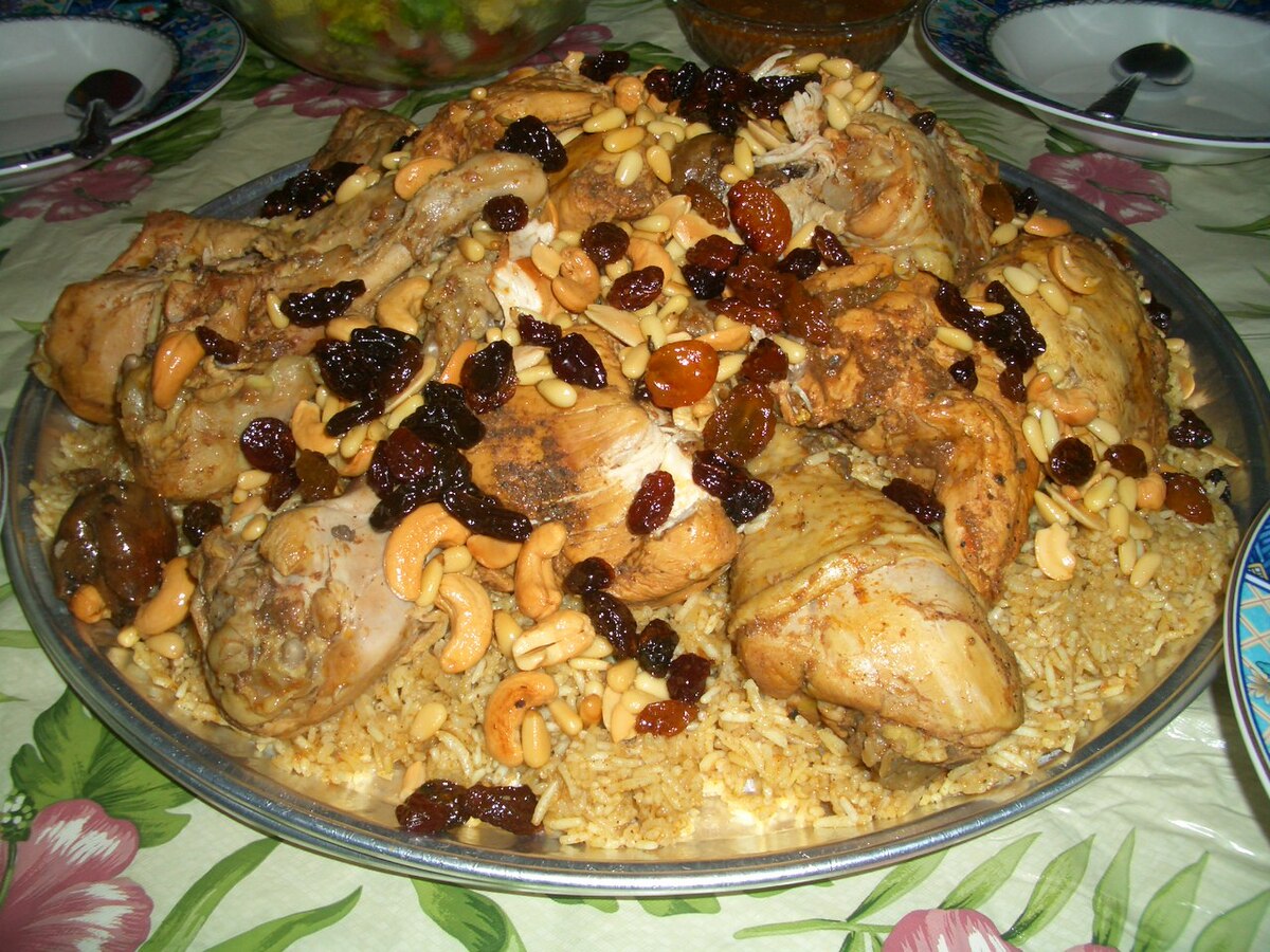 A traditional Saudi kabsa dish served on a large communal platter with chicken, rice, raisins and nuts