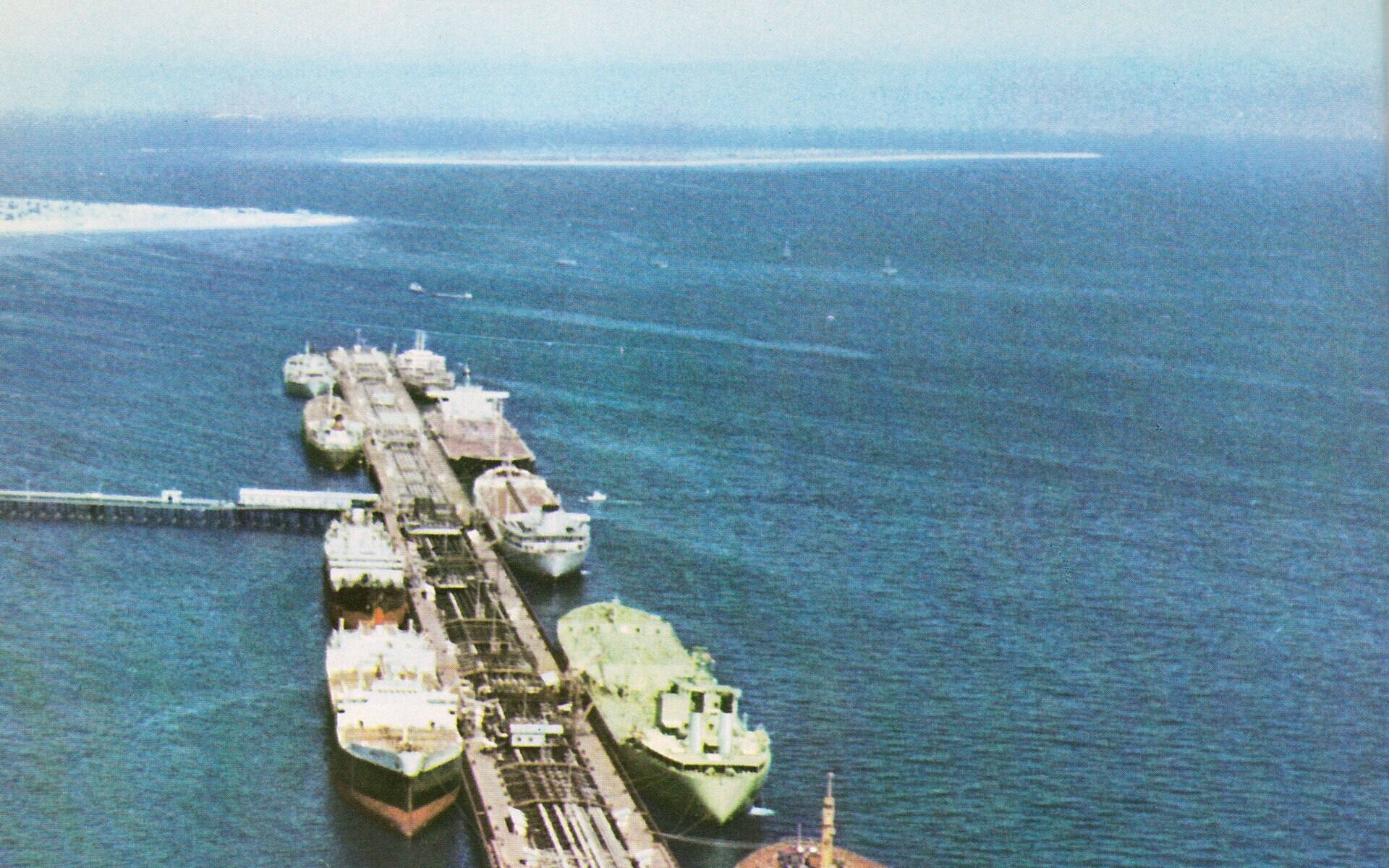 Kharg Island oil loading terminal with multiple tankers moored at the export pier — Kharg accounts for over 90% of Iranian crude exports and continued operating throughout the conflict, generating an estimated $3.5 billion in revenue for Iran as the sole exporter out of Hormuz