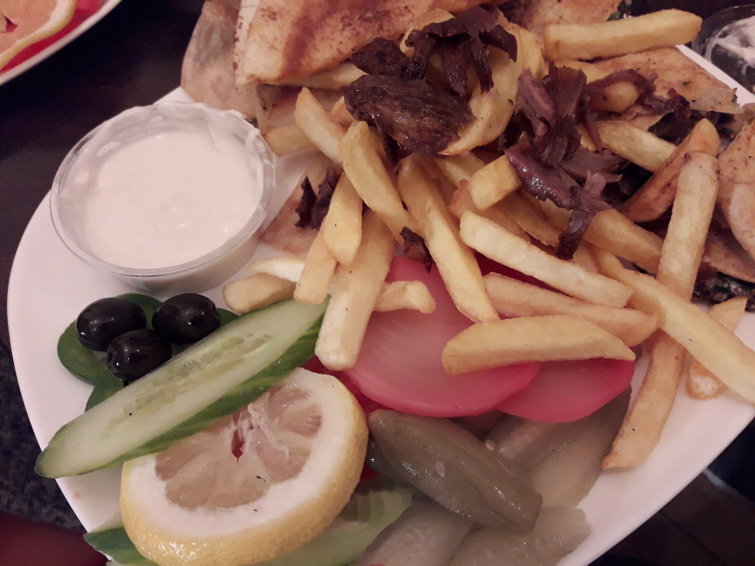 Arabic shawarma plate with pita, fries, pickles, olives and garlic sauce