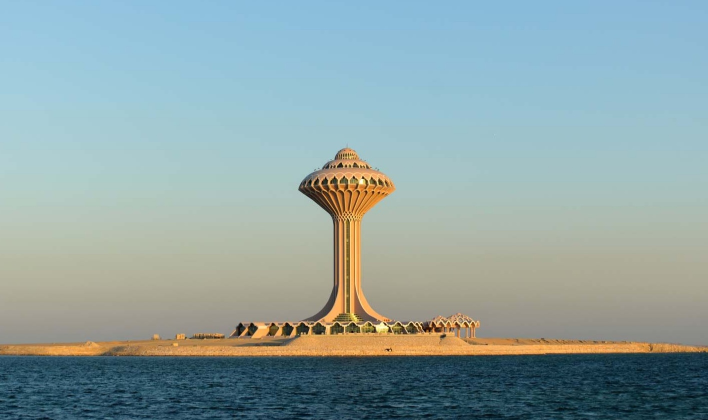 The Al Khobar Water Tower rising from its artificial island at sunset, reflected in the calm waters of the Arabian Gulf