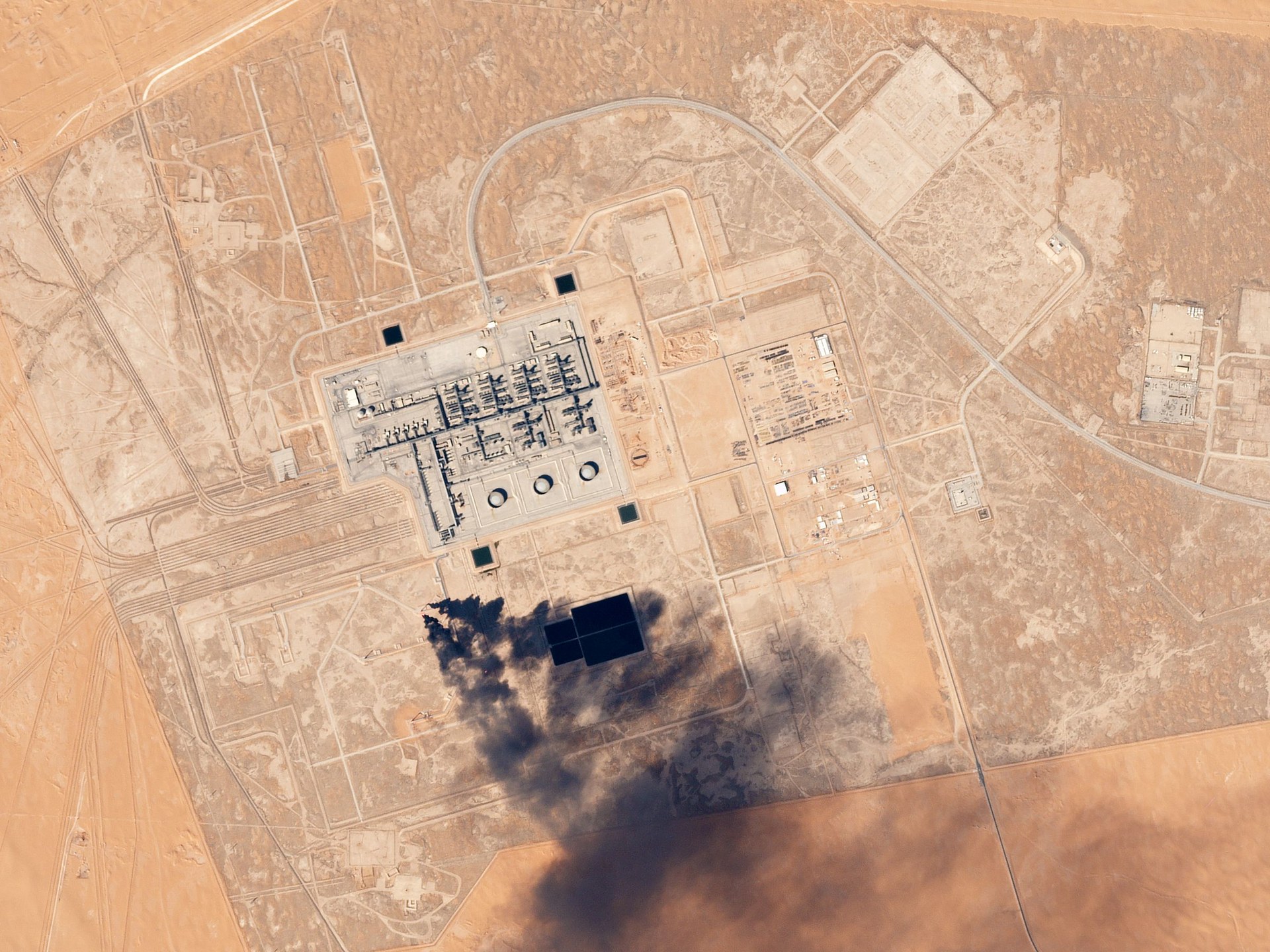Satellite image of Khurais Oil Processing Facility in Saudi Arabia with smoke plume visible from infrastructure damage