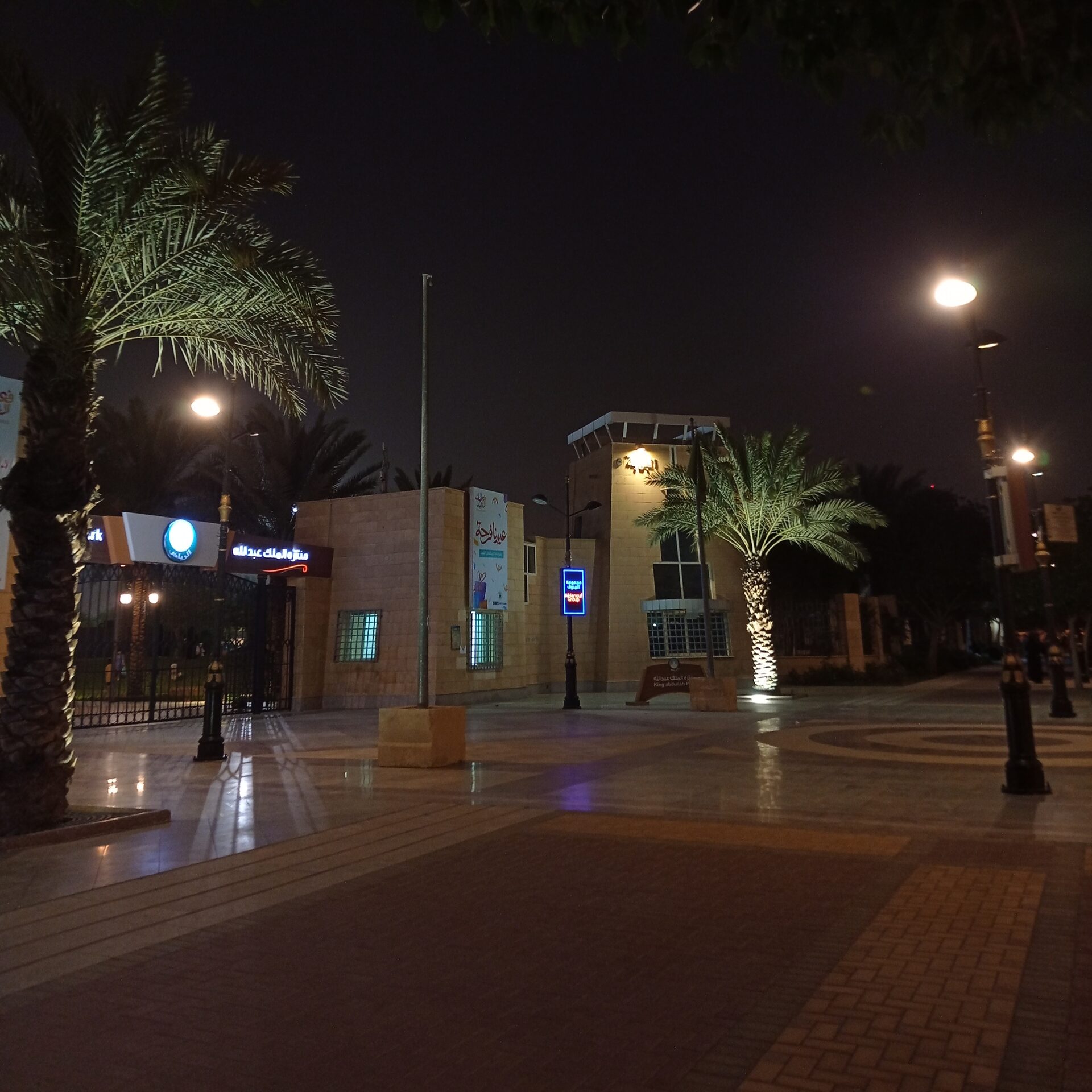 The illuminated entrance of King Abdullah Park in Riyadh at night with palm trees and stone architecture