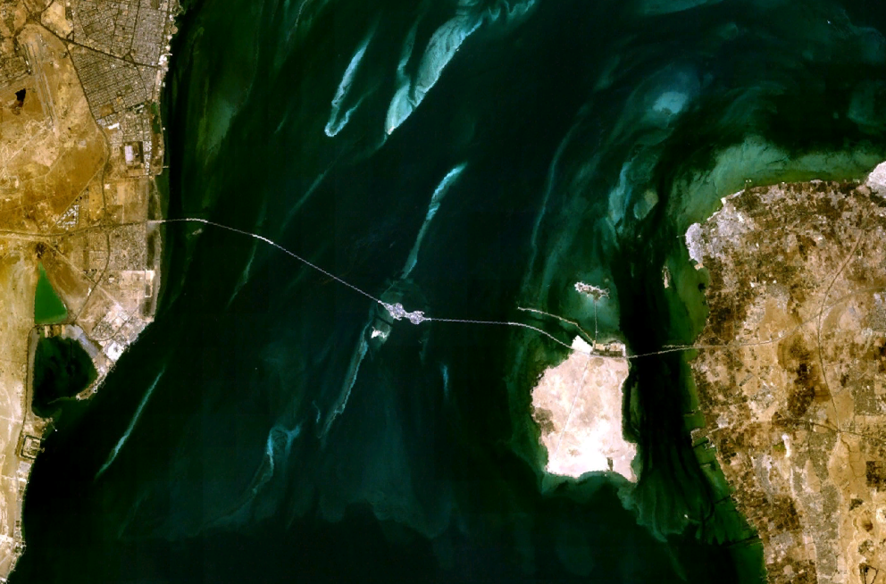 Satellite image of the King Fahd Causeway linking Saudi Arabia on the left to Bahrain on the right, with Passport Island visible at the midpoint
