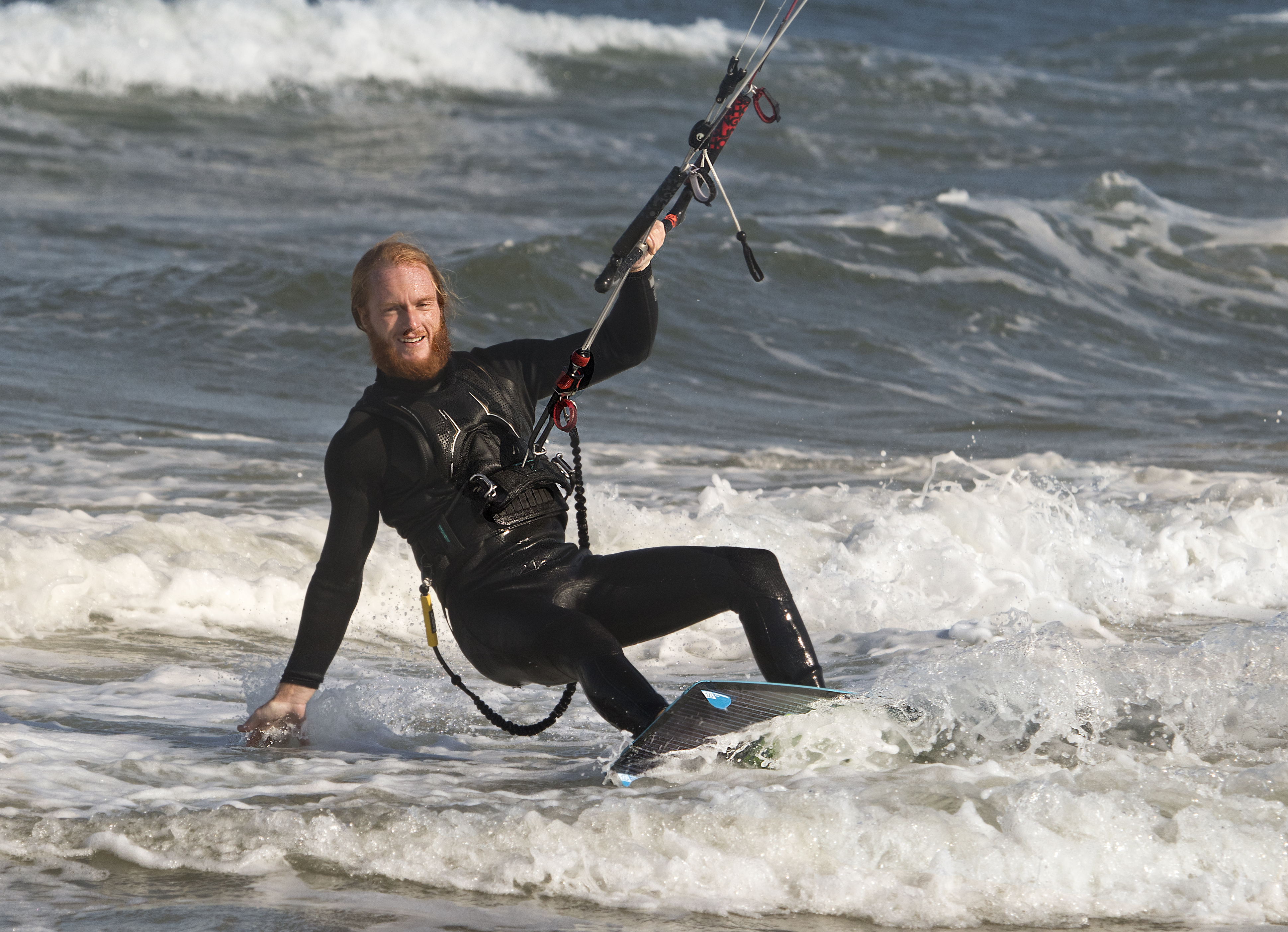 Kitesurfer launching into the air above blue ocean water