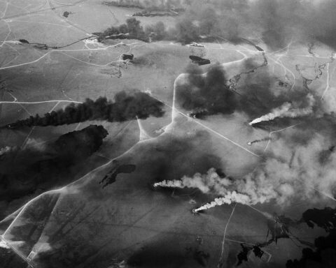 Aerial view of Kuwaiti oil well fires burning across the desert, black smoke plumes rising from multiple strike points