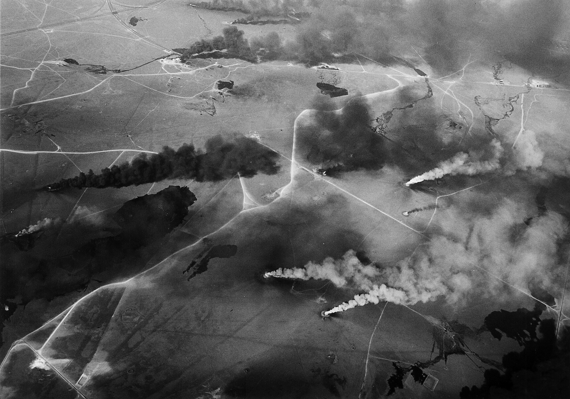 Aerial view of Kuwaiti oil well fires burning across the desert, black smoke plumes rising from multiple strike points