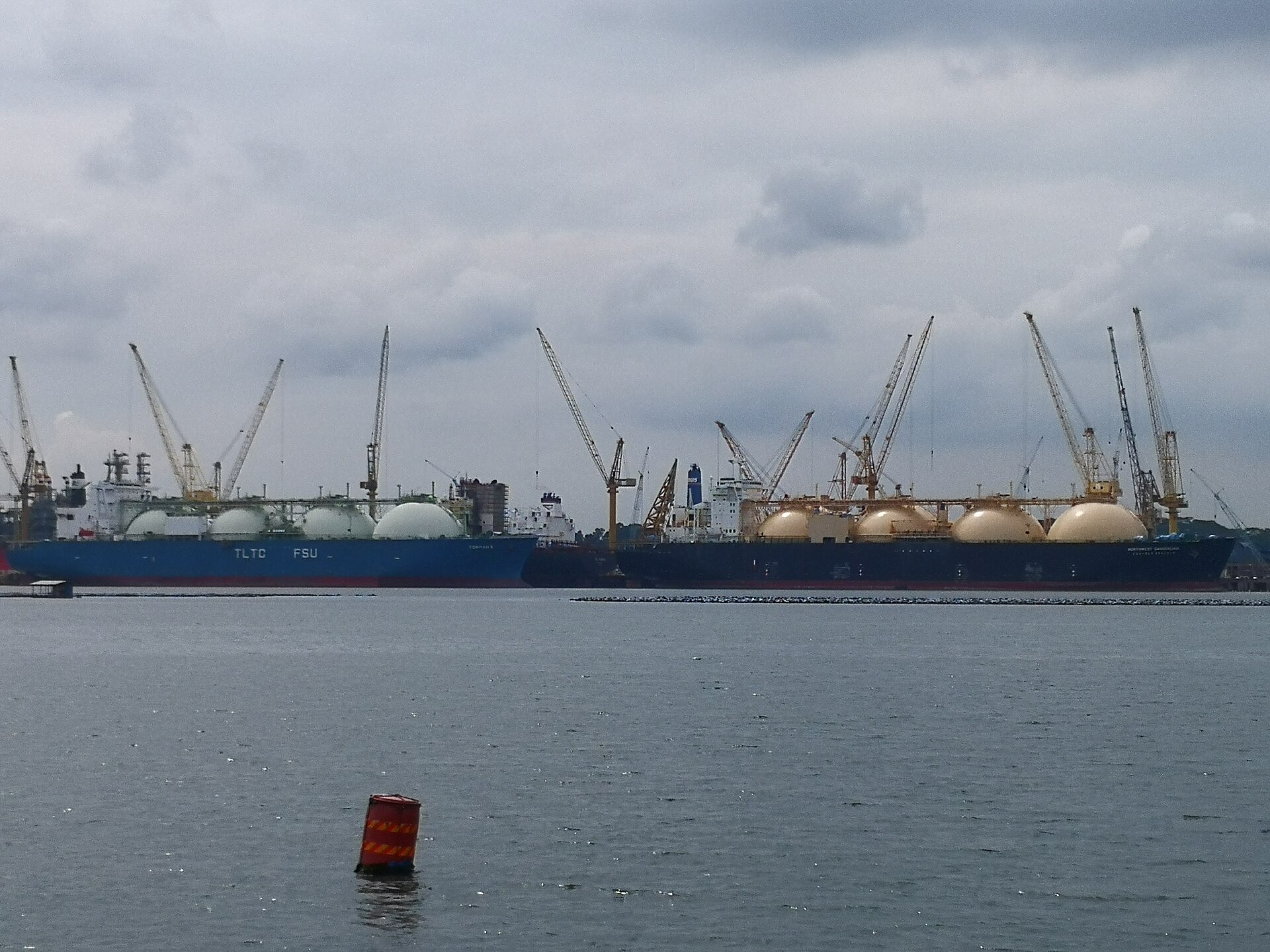 Multiple LNG carriers with spherical Moss-type tanks docked at Singapore harbor, illustrating the global LNG fleet that depends on uninterrupted transit through key shipping chokepoints including the Strait of Hormuz