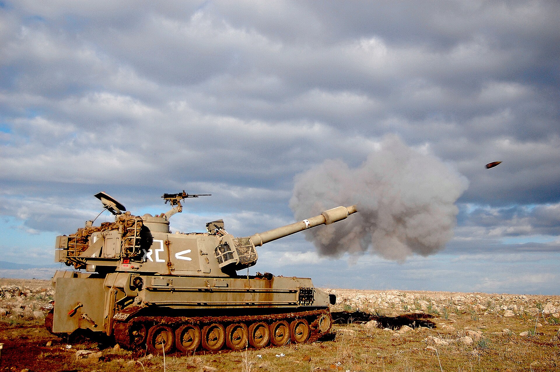 M109 self-propelled 155mm howitzer firing in rocky arid terrain