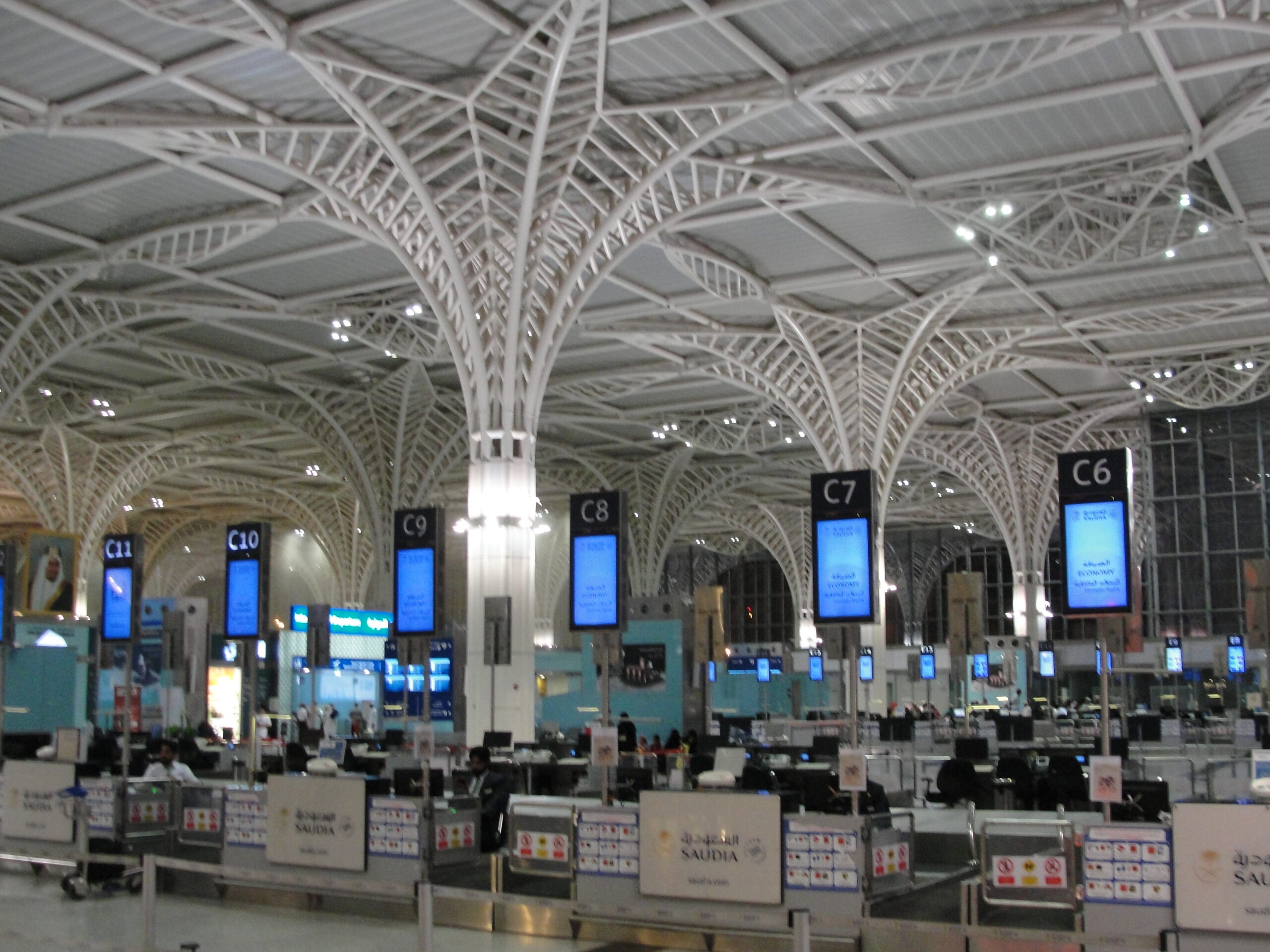 Interior of Prince Mohammad Bin Abdulaziz Airport showing steel palm-tree columns and check-in counters