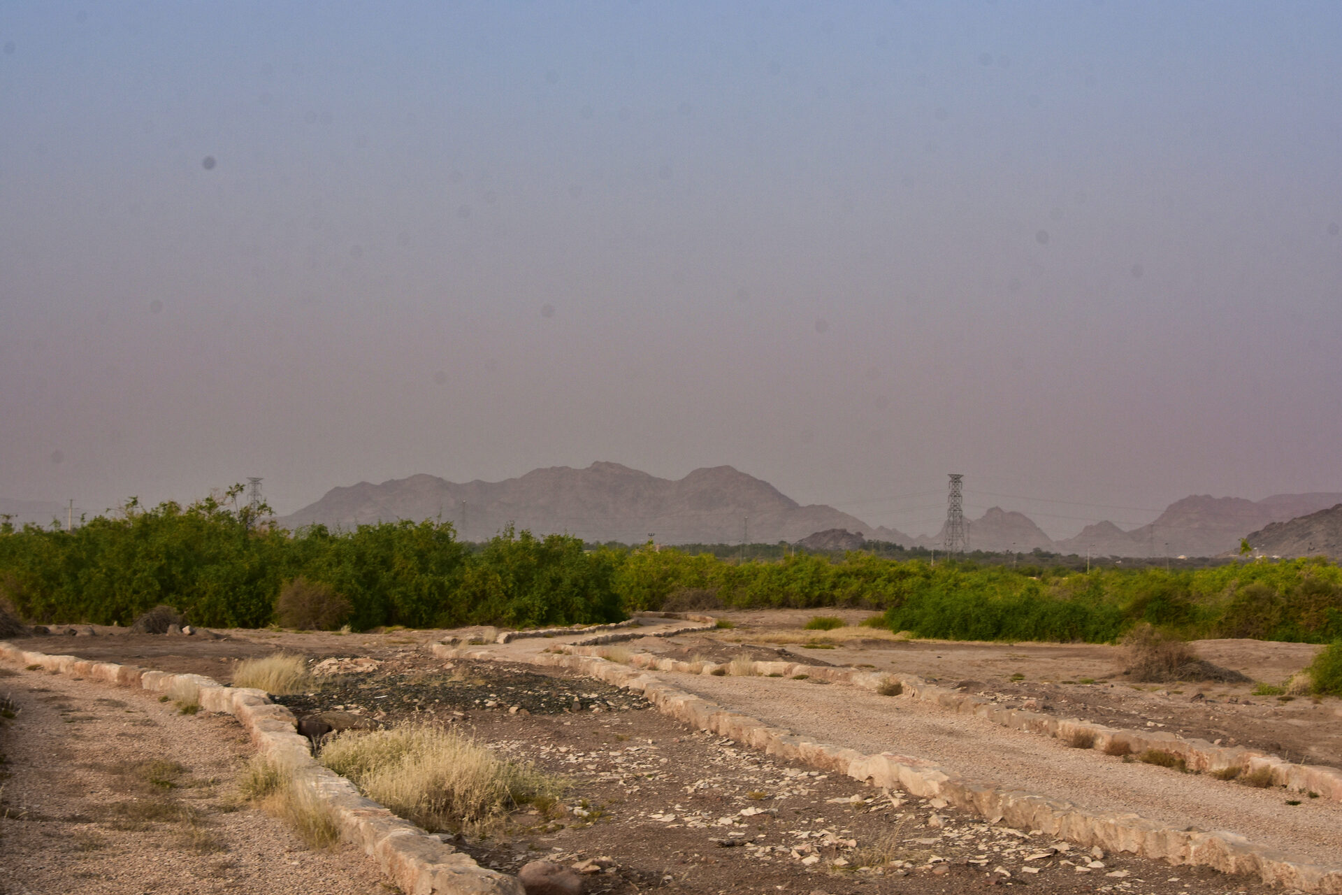 Ancient stone foundations at the Al-Ukhdood archaeological site in Najran, with mountains visible in the background