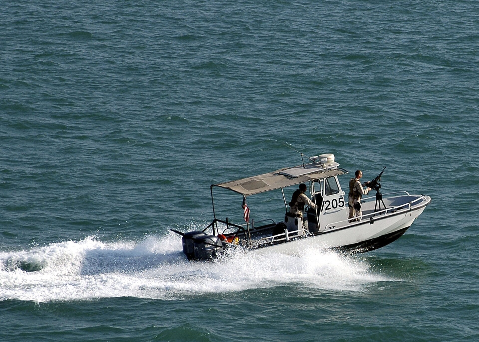Naval Security Force Bahrain harbor patrol boat escorts USS Saipan at NSA Bahrain, Fifth Fleet headquarters in Manama, 2006