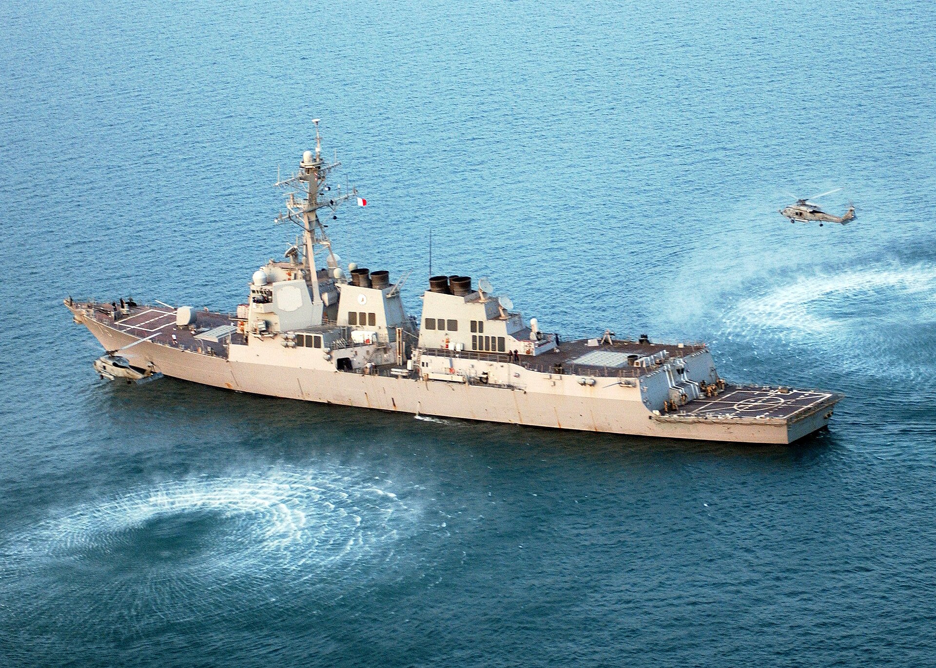 USS Oscar Austin (DDG-79), an Arleigh Burke-class guided-missile destroyer, underway in the Persian Gulf flanked by Seahawk helicopters during Maritime Security Operations.