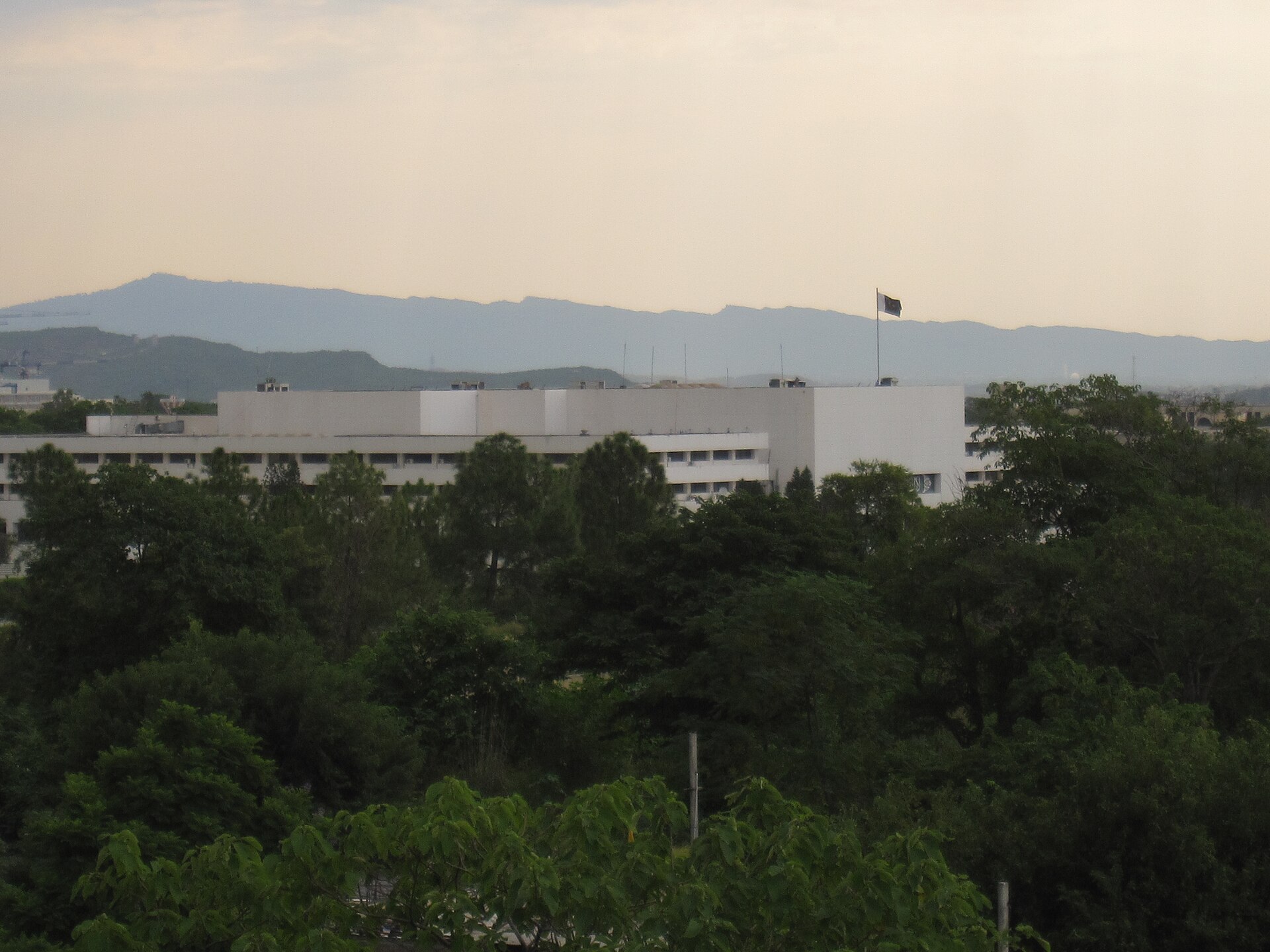 Pakistan Parliament House in Islamabad with national flag, Margalla Hills in background