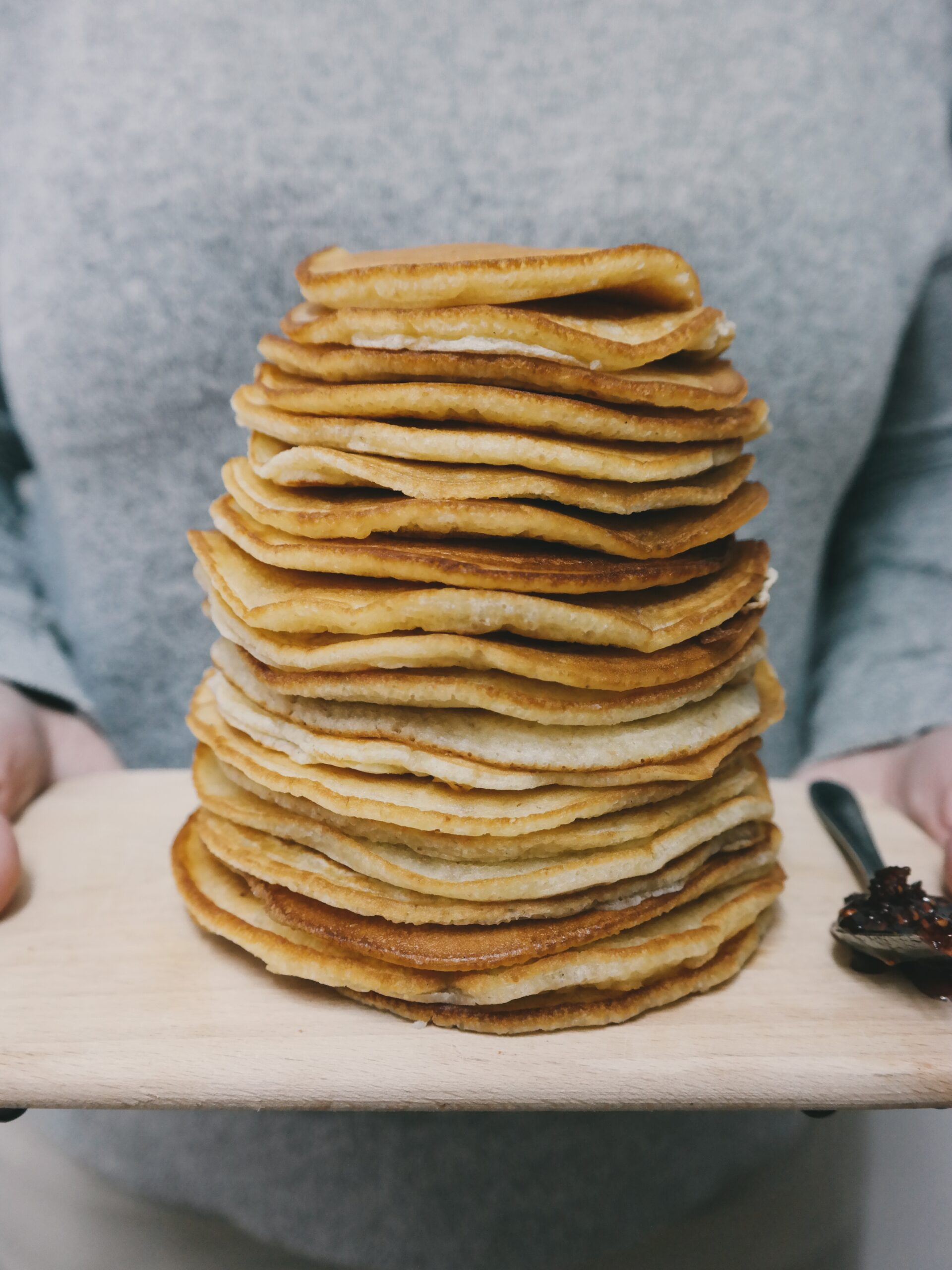 Tall stack of fluffy pancakes on a wooden board, a popular brunch dish across Jeddah cafes