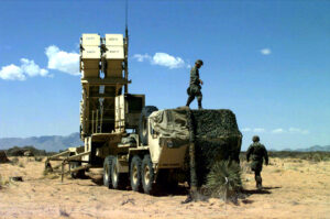 A Patriot PAC-3 missile launcher emplaced in desert terrain at Fort Bliss, Texas — identical to batteries now deployed around Mecca and Medina. Each launcher holds 16 interceptors at $3.9 million each; Saudi Arabia has consumed roughly 2,400 rounds in 38 days of war, leaving approximately 400 remaining. Photo: US Army / Public Domain