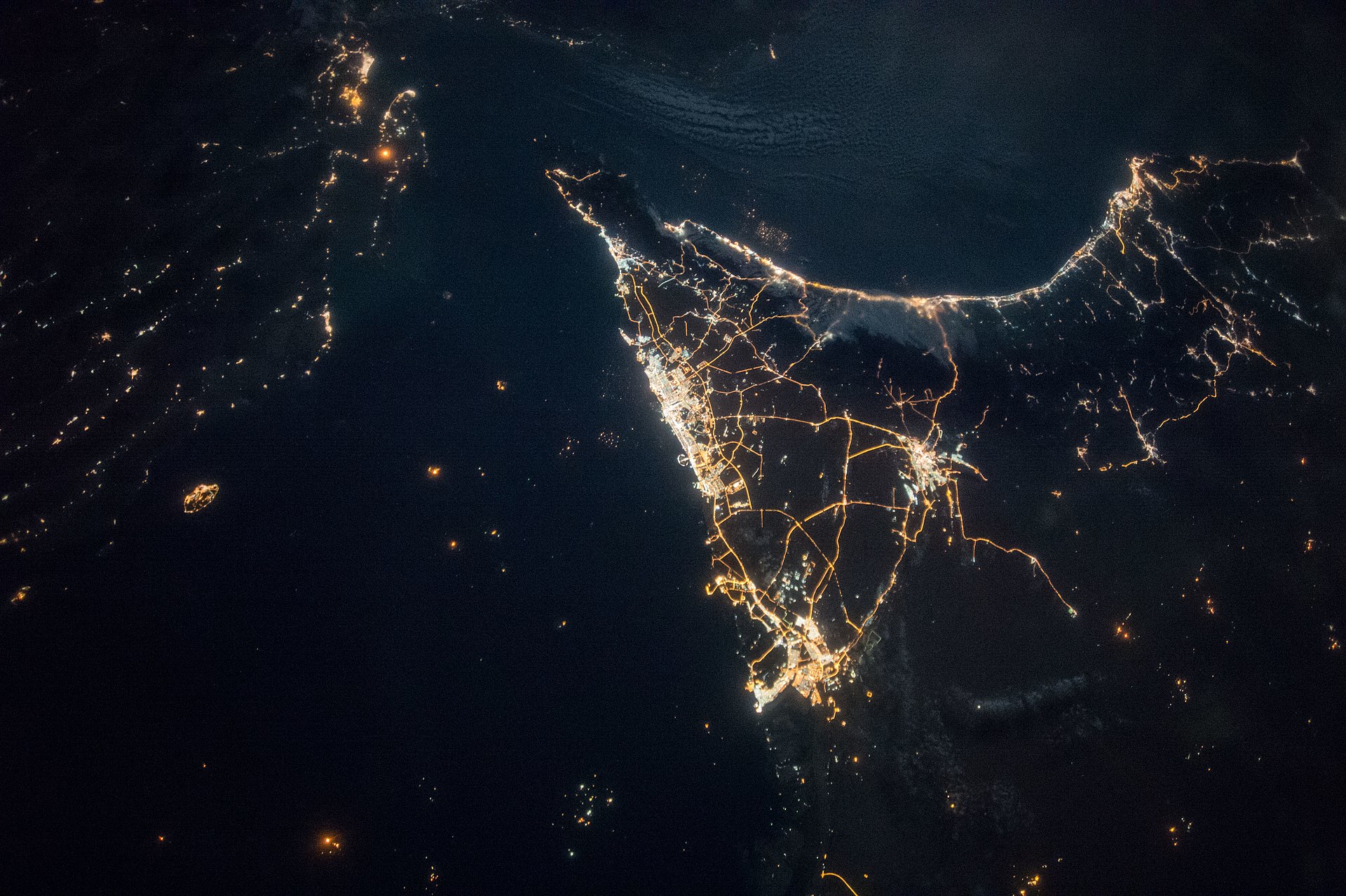 Night satellite view of Dubai and Abu Dhabi from the International Space Station, with Iran visible to the upper left across the Persian Gulf — the commercial heartland whose oil trade China became the indispensable broker to reopen