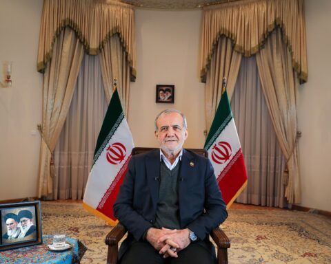 Iranian President Masoud Pezeshkian seated with Iranian flags in formal interview setting, 2025
