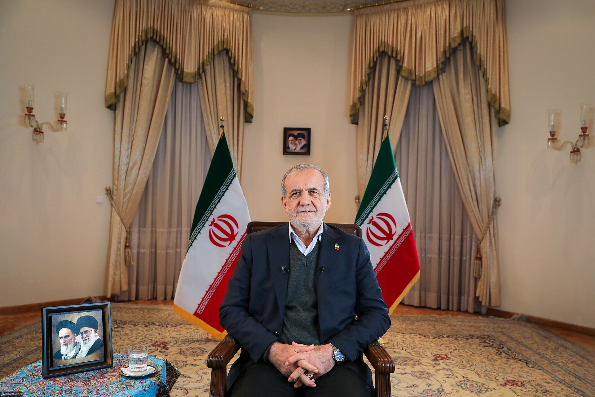 Iranian President Masoud Pezeshkian seated with Iranian flags in formal interview setting, 2025