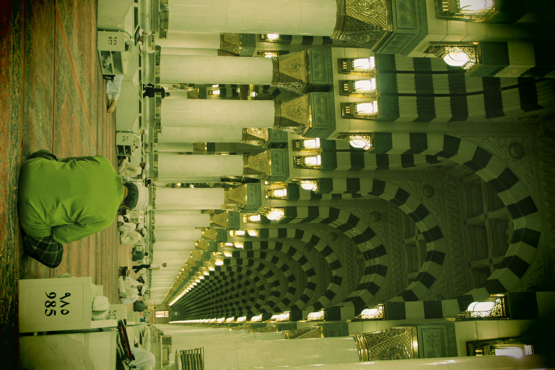 Interior colonnade of the Prophet's Mosque in Medina with arched columns and ornate Islamic architecture