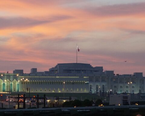 Qatar Amiri Diwan government seat Doha at dusk with Qatari flag