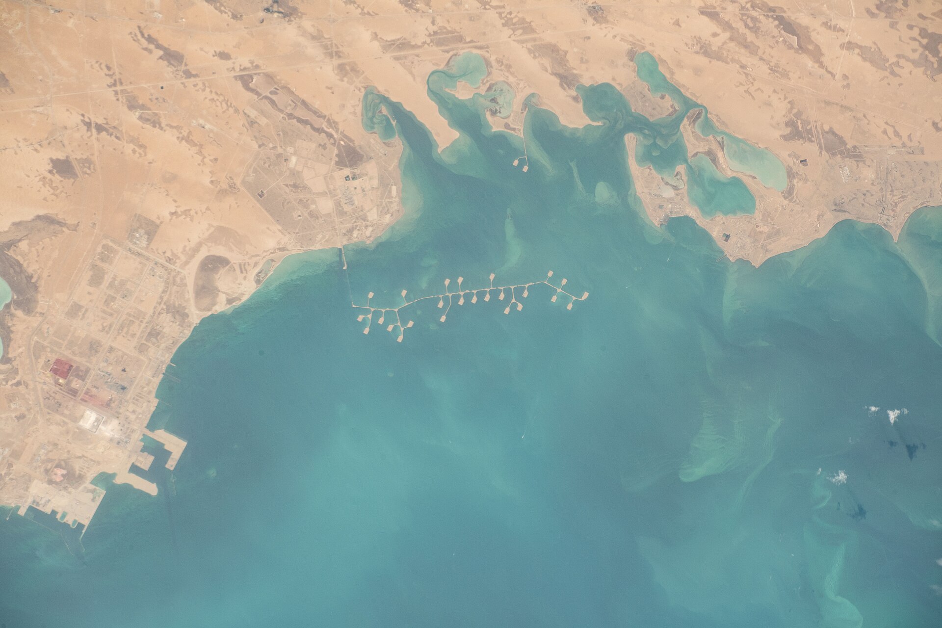 ISS astronaut photograph of Saudi Arabia's Eastern Province Gulf coast showing the industrial port complex at Ras Al-Khair, with the shallow teal waters of the Persian Gulf directly adjacent to the desalination and industrial infrastructure
