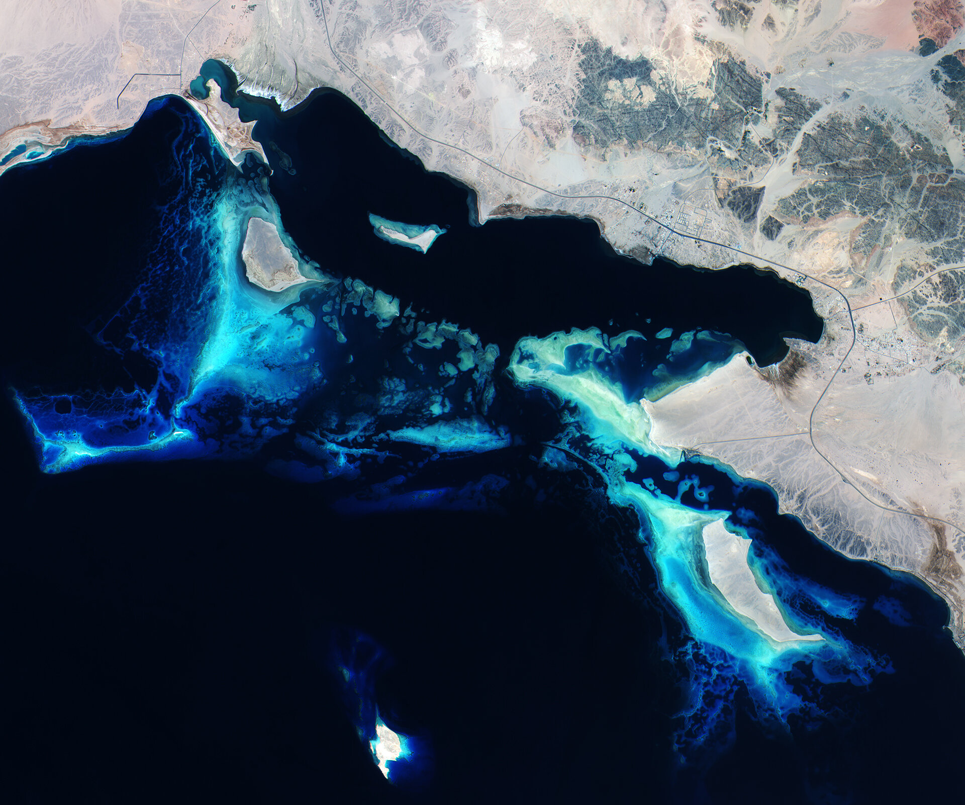 Satellite view of Red Sea coral reef formations off the Saudi Arabian coast, showing vivid turquoise shallow reefs against deep blue water