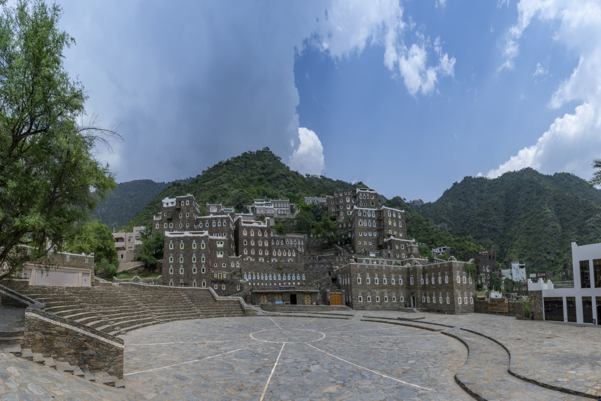 Rijal Almaa heritage village with traditional multi-storey stone buildings set against green mountains in Asir