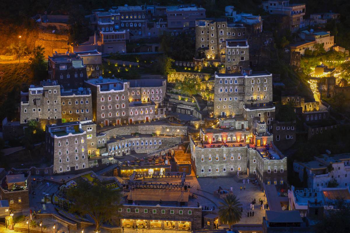 Rijal Almaa heritage village illuminated at night with warm lighting on stone towers