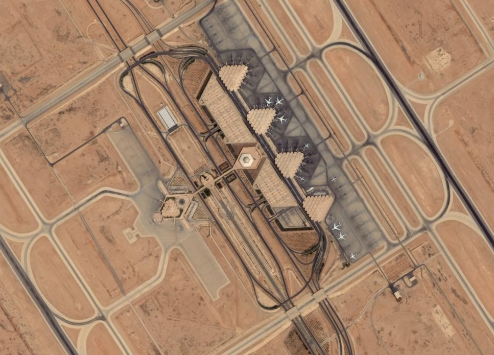 Aerial satellite view of King Khalid International Airport showing the distinctive triangular terminal design and dual runways