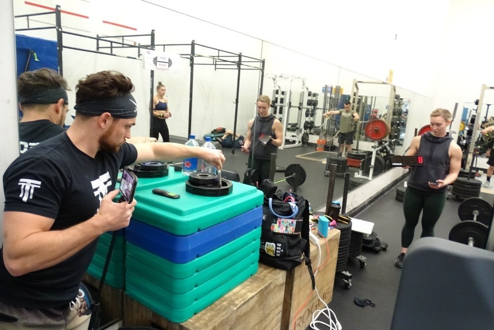 Athletes training with barbells and functional fitness equipment in a CrossFit gym