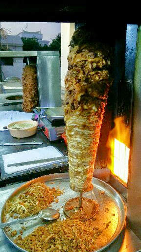 Shawarma meat rotating on a vertical rotisserie spit, the traditional cooking method used across Riyadh restaurants