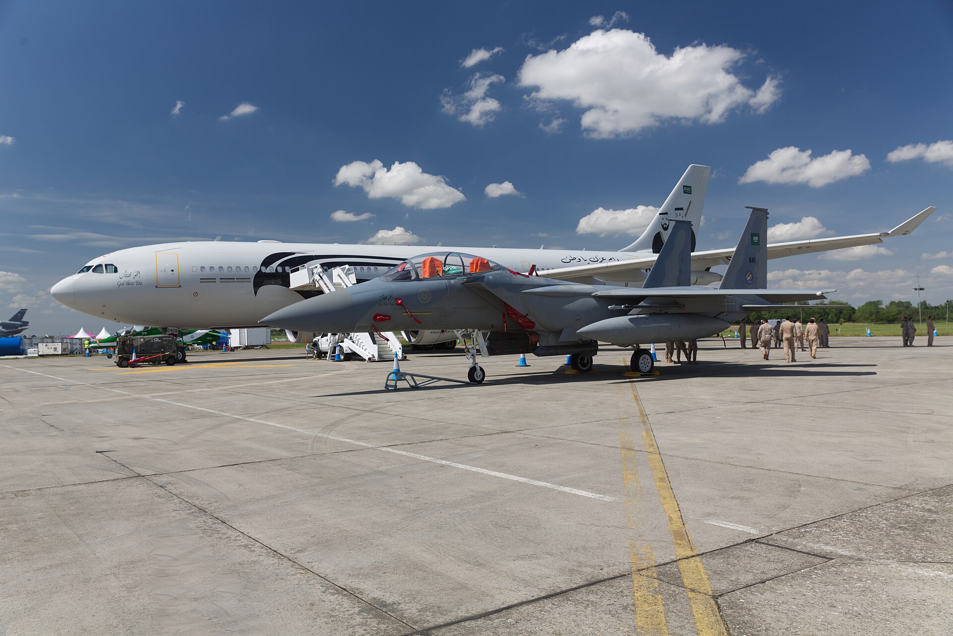 Royal Saudi Air Force F-15SA fighter jet on the tarmac alongside an RSAF A330 MRTT tanker aircraft, showing Saudi Air Force markings and Arabic inscriptions