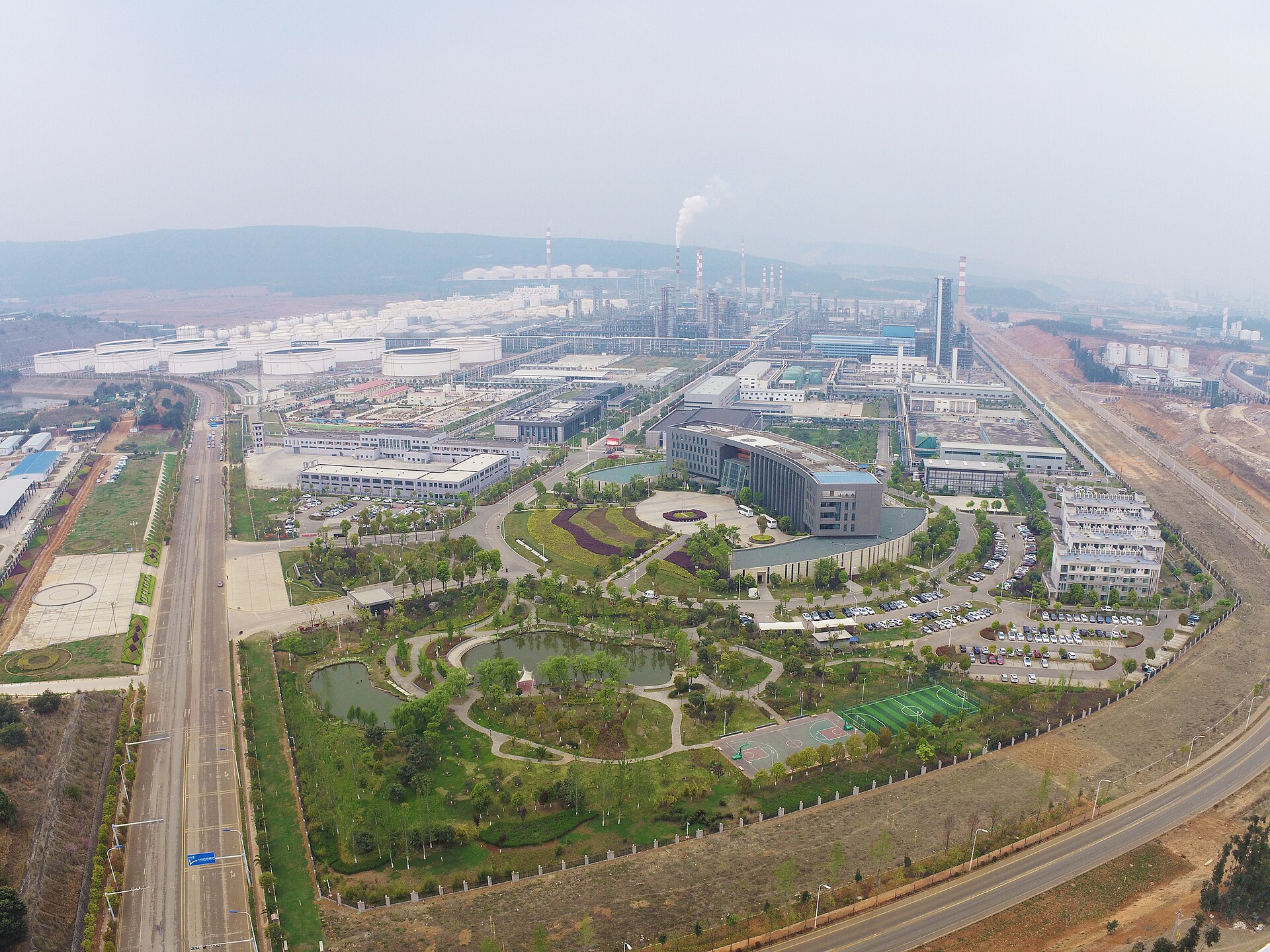 Aerial view of a large-scale petroleum refinery complex with storage tanks, distillation columns, and processing infrastructure — representative of the industrial scale of the SAMREF joint venture at Yanbu