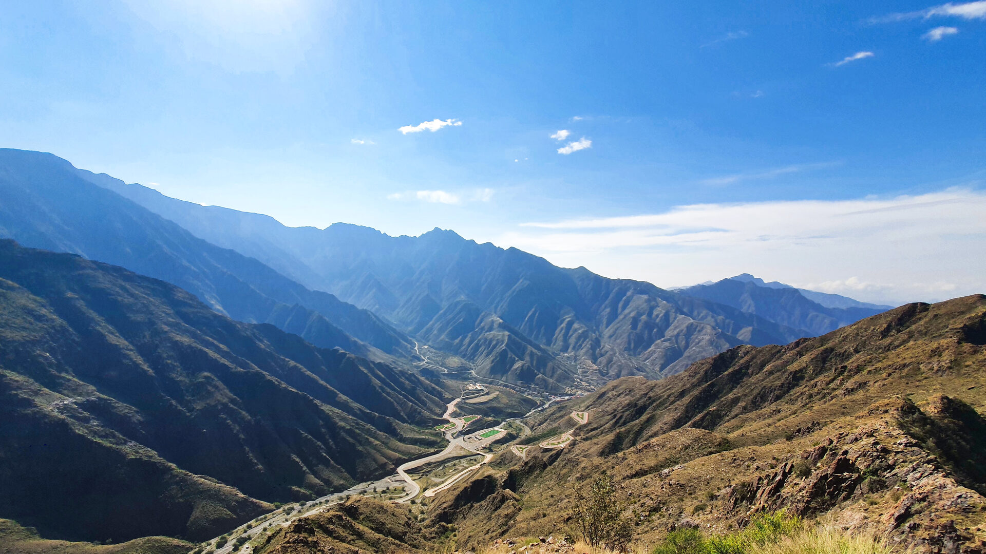 Panoramic view of the Sarawat Mountains in the Asir region showing winding mountain roads and dramatic valleys