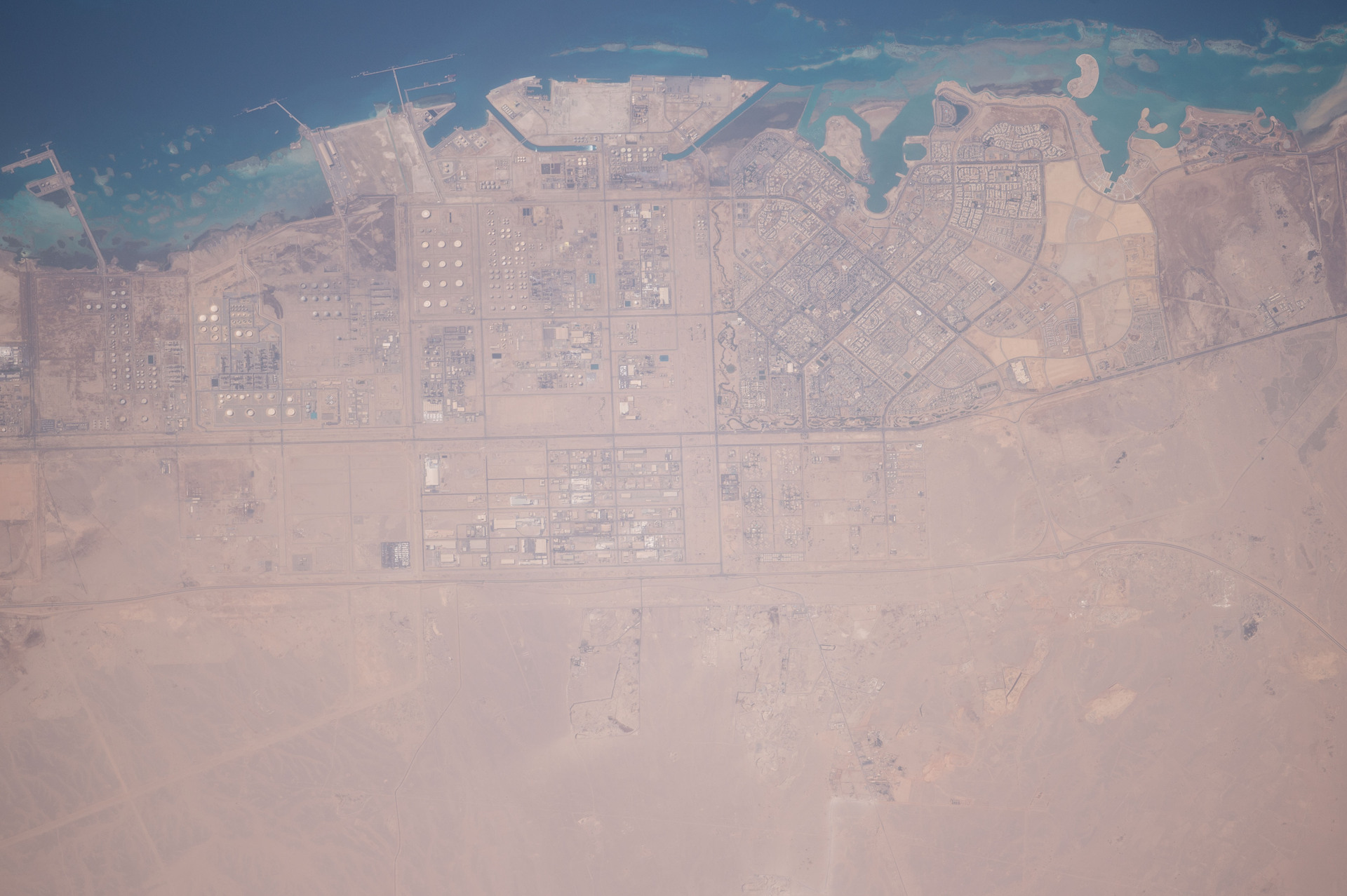 Saudi Arabian oil and gas processing facility photographed from the International Space Station, showing storage tanks and refinery infrastructure along the Persian Gulf coast