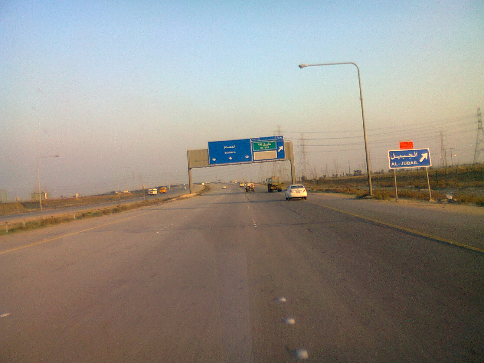 Multi-lane Saudi Arabian desert highway stretching into the haze with road signs