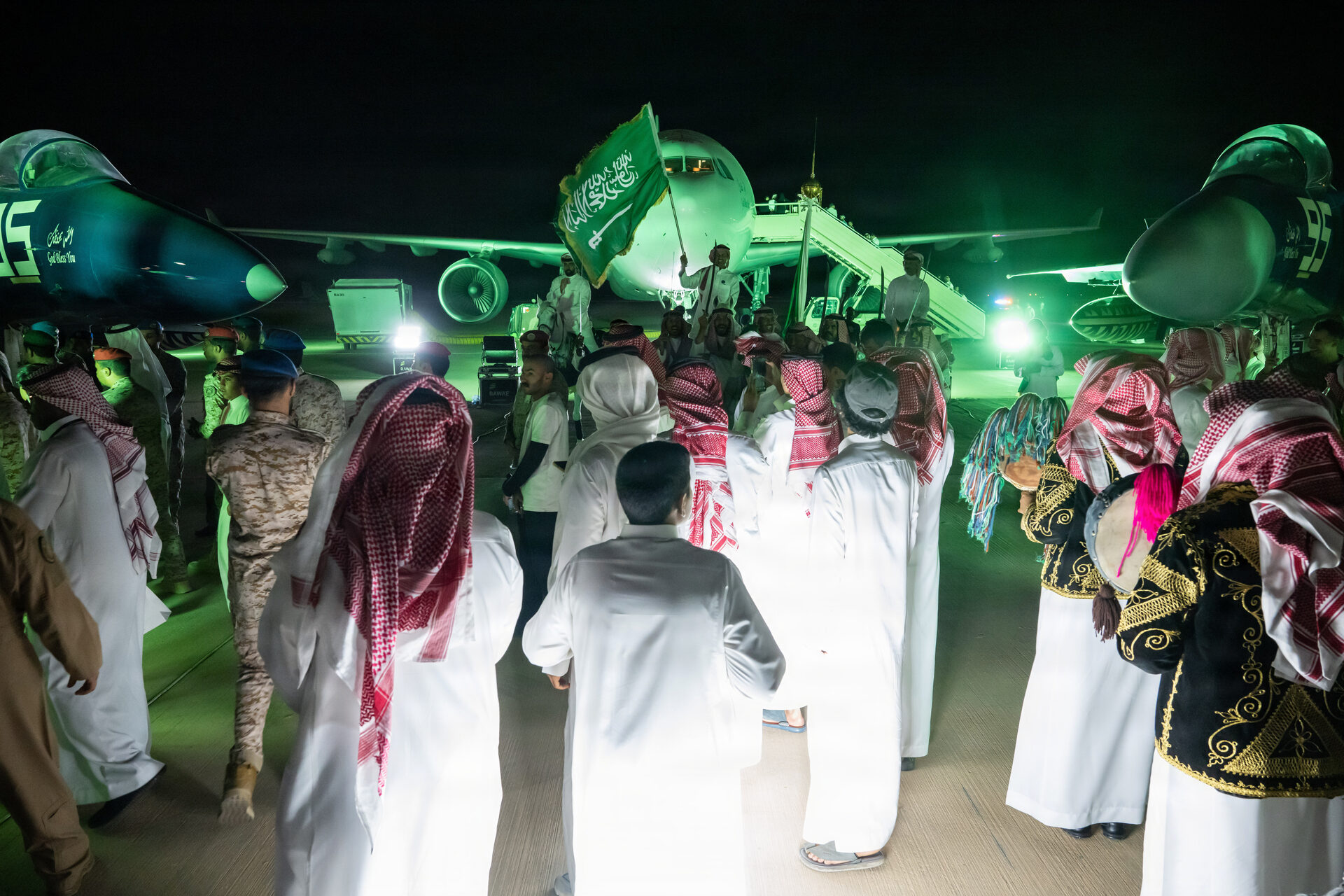 Saudi citizens in traditional dress waving green flags during 95th Saudi National Day celebrations