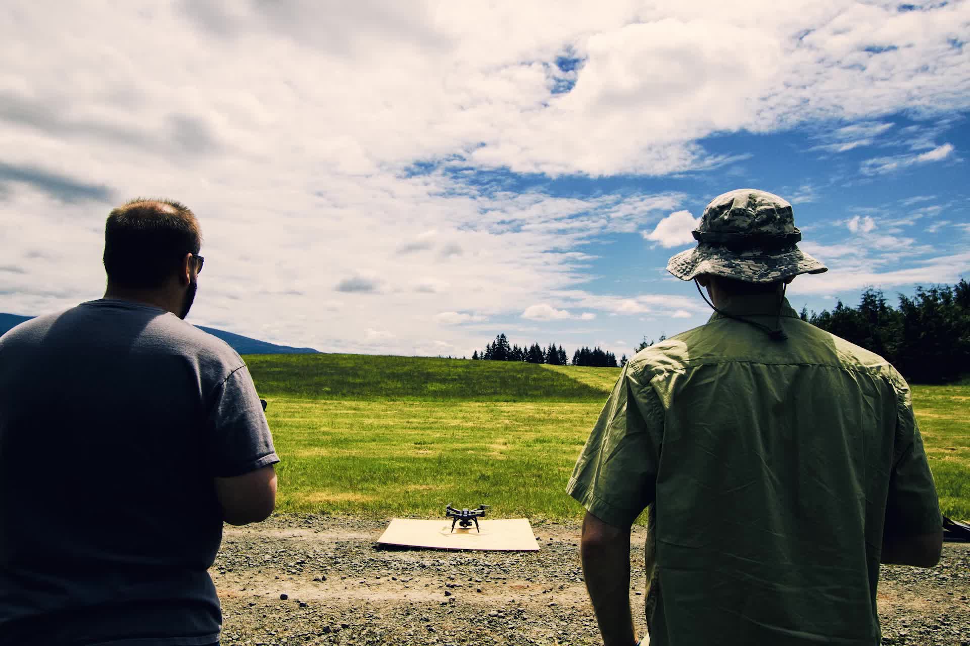 Two drone operators preparing a quadcopter for aerial photography flight