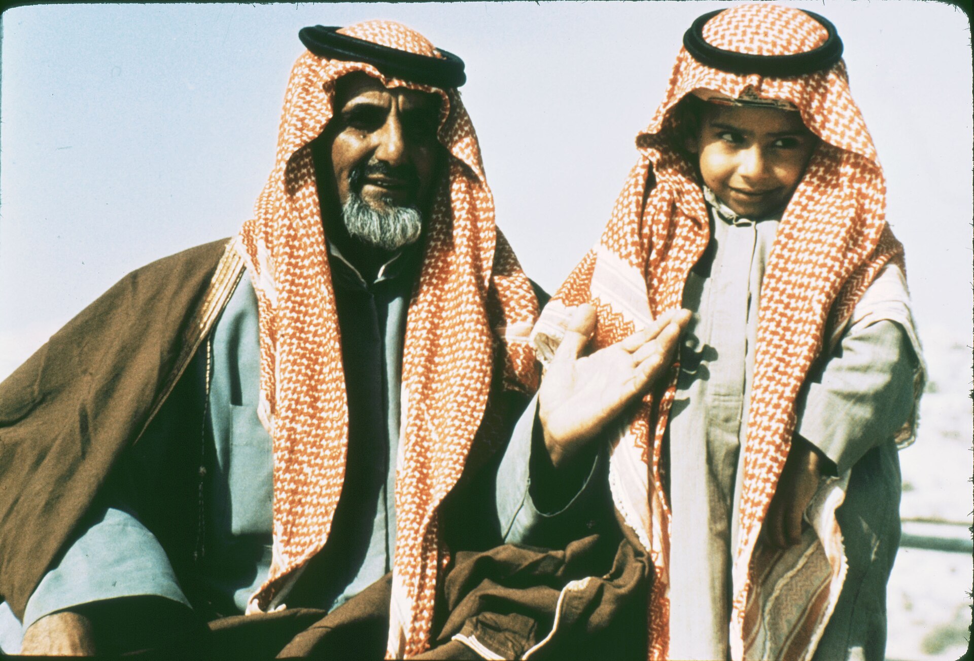 A Saudi father and son wearing traditional thobe and keffiyeh headwear