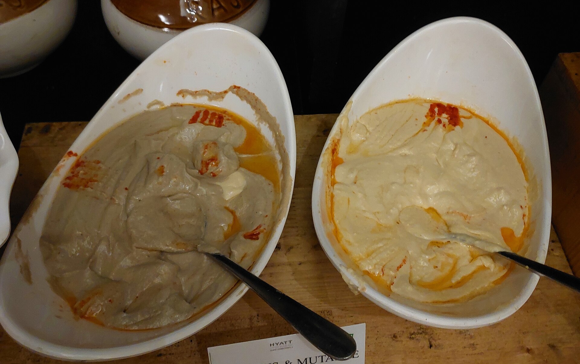 Bowls of hummus and mutabbal (smoky eggplant dip) drizzled with olive oil and paprika, two vegan staples of Saudi cuisine