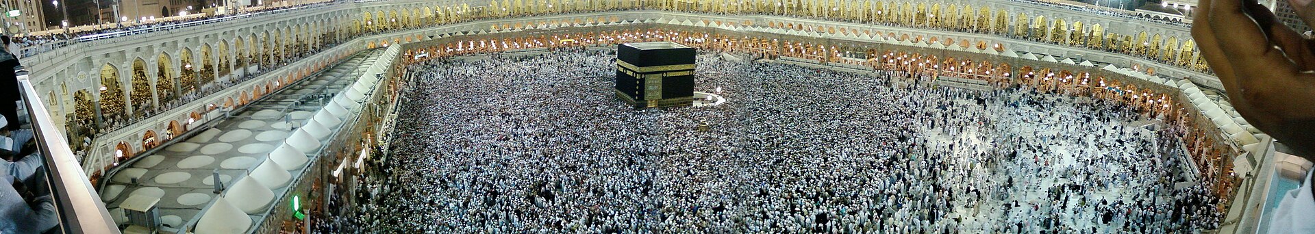 Panoramic view of Masjid al-Haram in Mecca during prayer, with the Kaaba at the centre surrounded by hundreds of thousands of worshippers