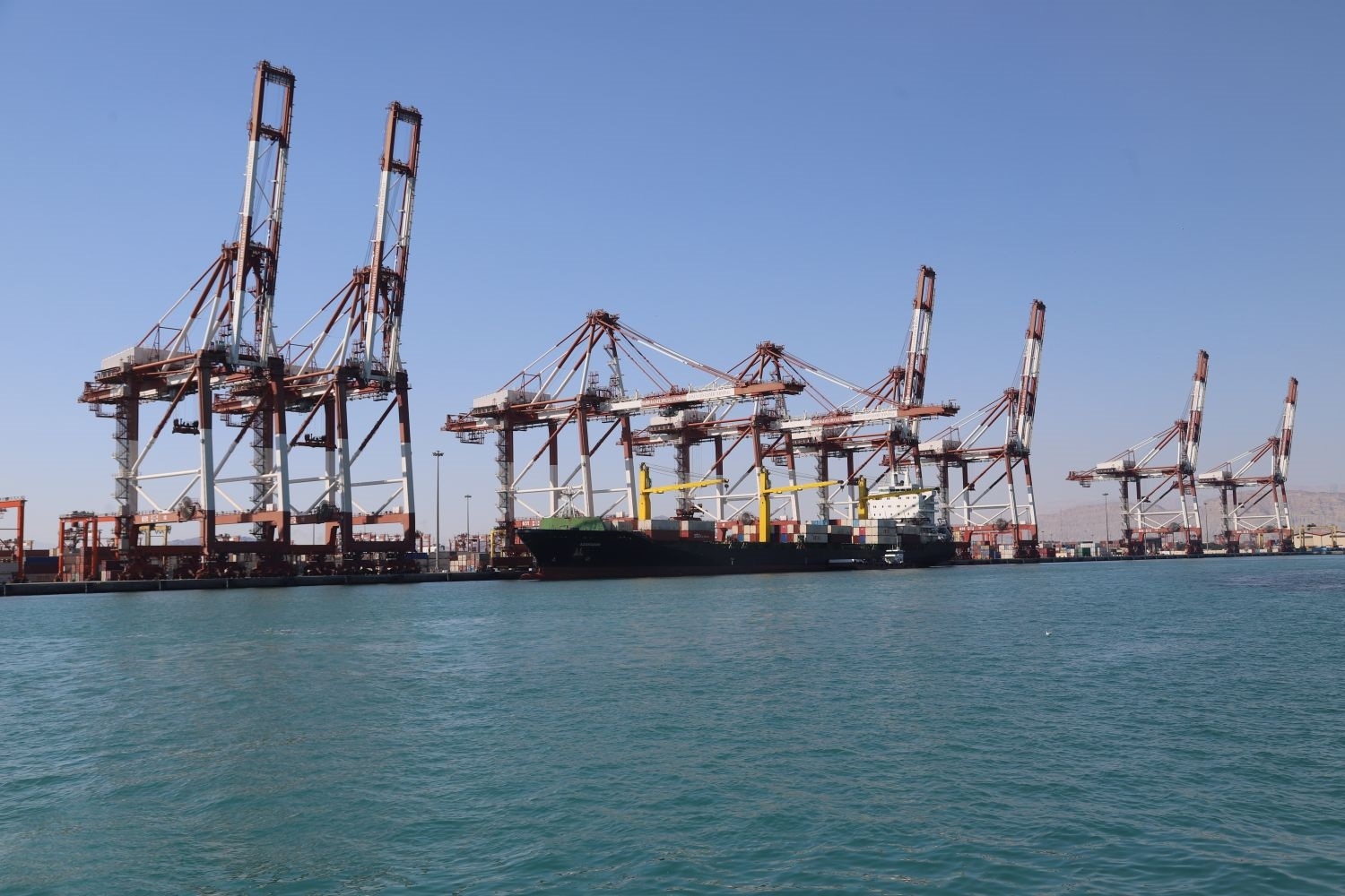 Shahid Rajaei port container cranes and cargo ship at Bandar Abbas, Iran — the port handles 85-90% of Iran's container traffic