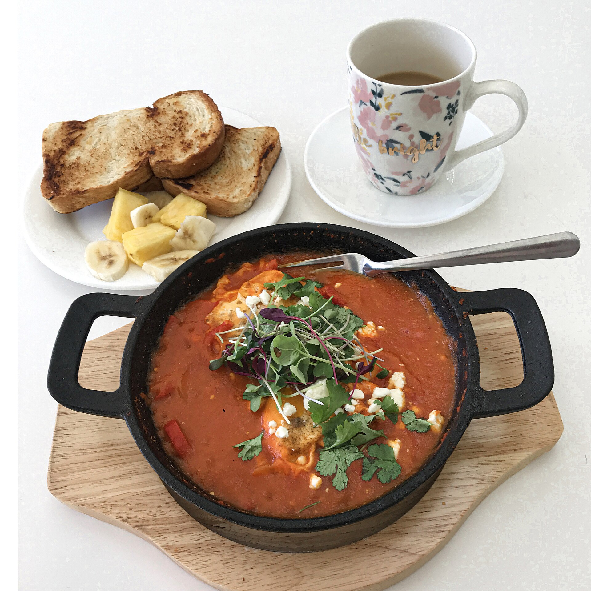 Shakshuka served in a cast-iron skillet with toast and tea, a staple of Jeddah brunch menus