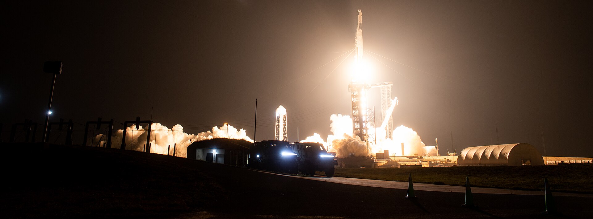 SpaceX Falcon 9 rocket launching NASA Crew-6 mission with long-exposure light trail against night sky at Kennedy Space Center