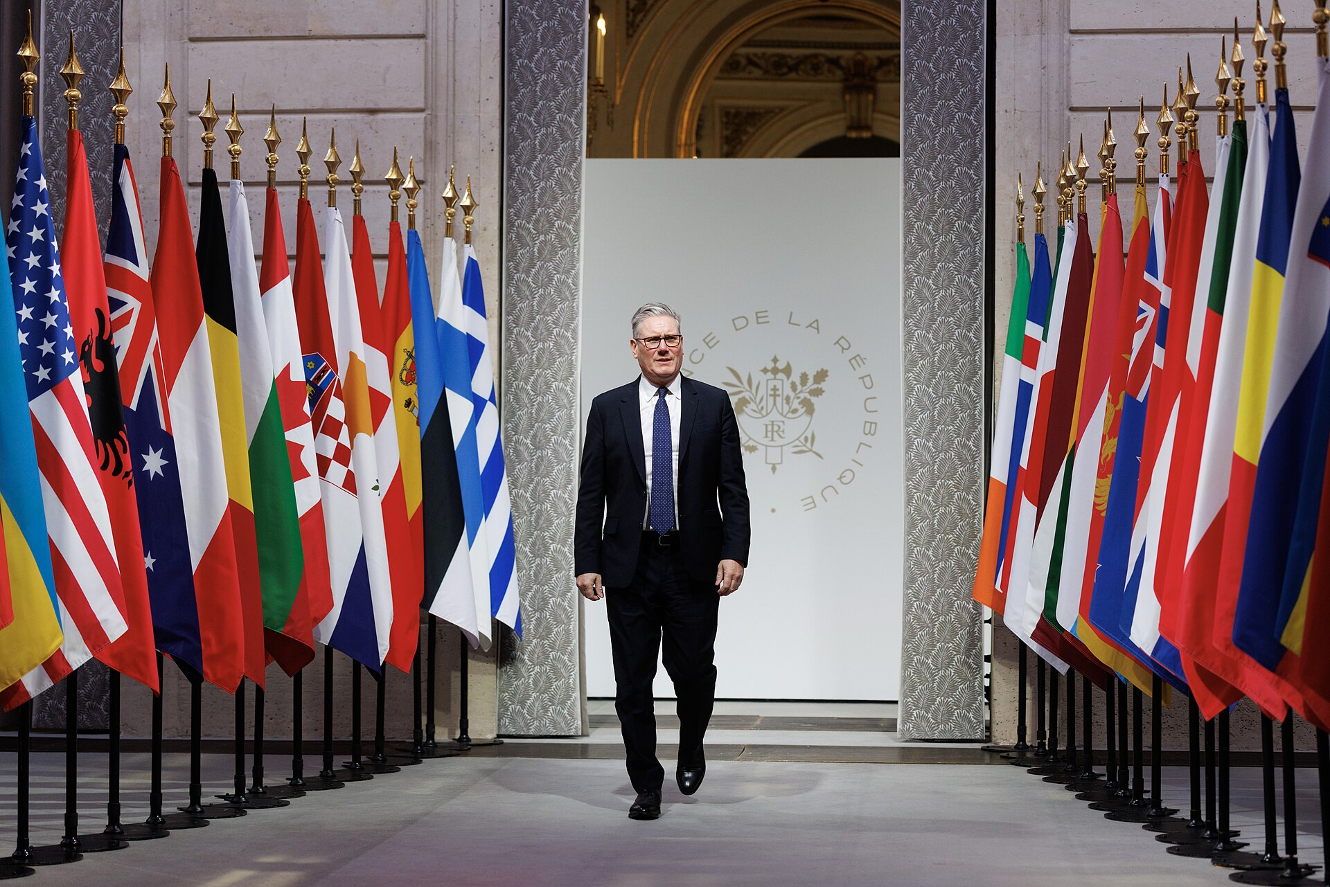 British Prime Minister Keir Starmer walks through the Palais de la République at the Coalition of the Willing summit hosted by French President Emmanuel Macron at the Élysée Palace, January 2026 — the same bilateral European coalition framework that convened again in April 2026 on Hormuz maritime freedom of navigation