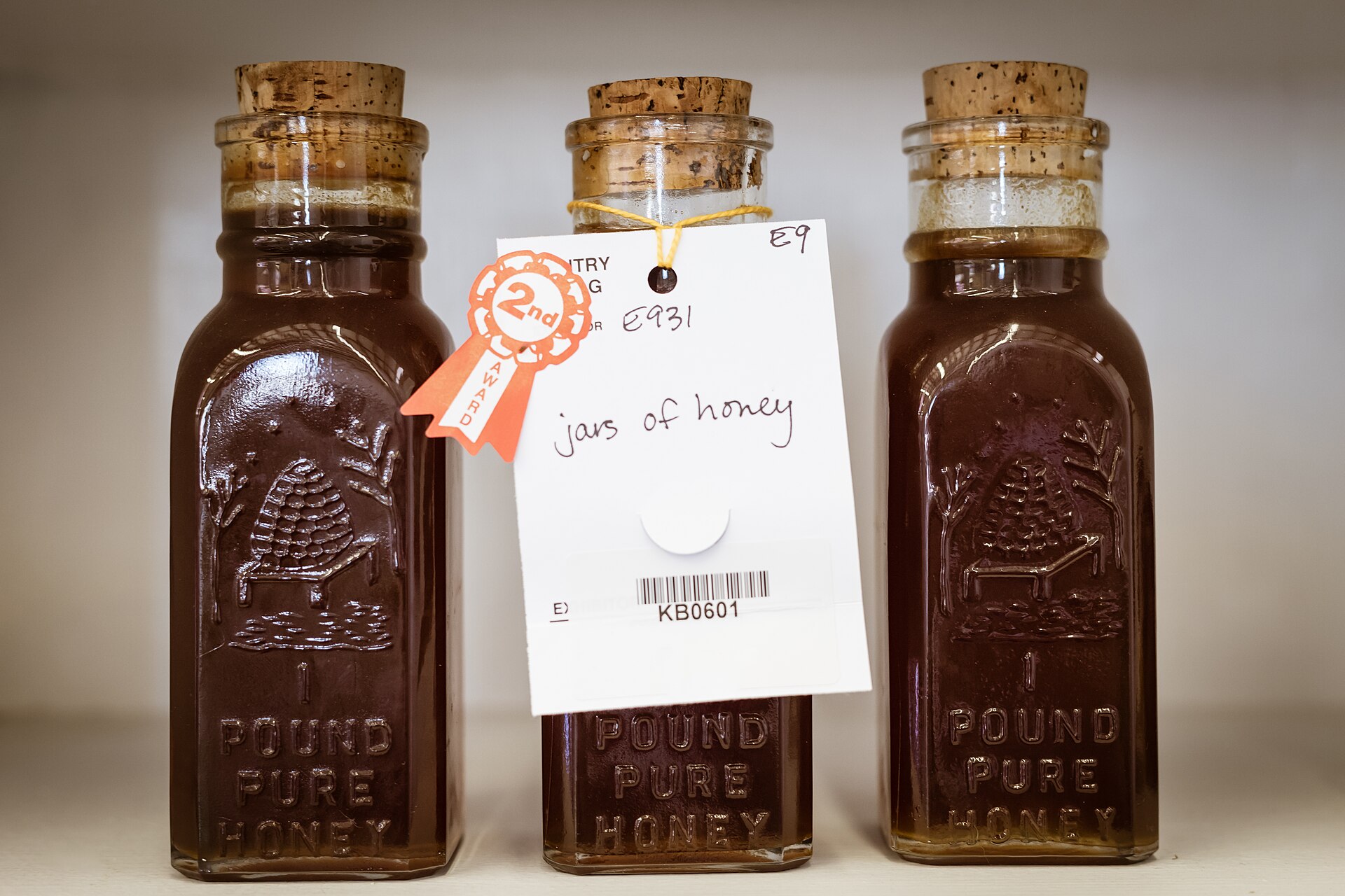 Artisan honey jars with cork stoppers displayed at a fair, similar to the traditional honey sold in Taif's mountain souks