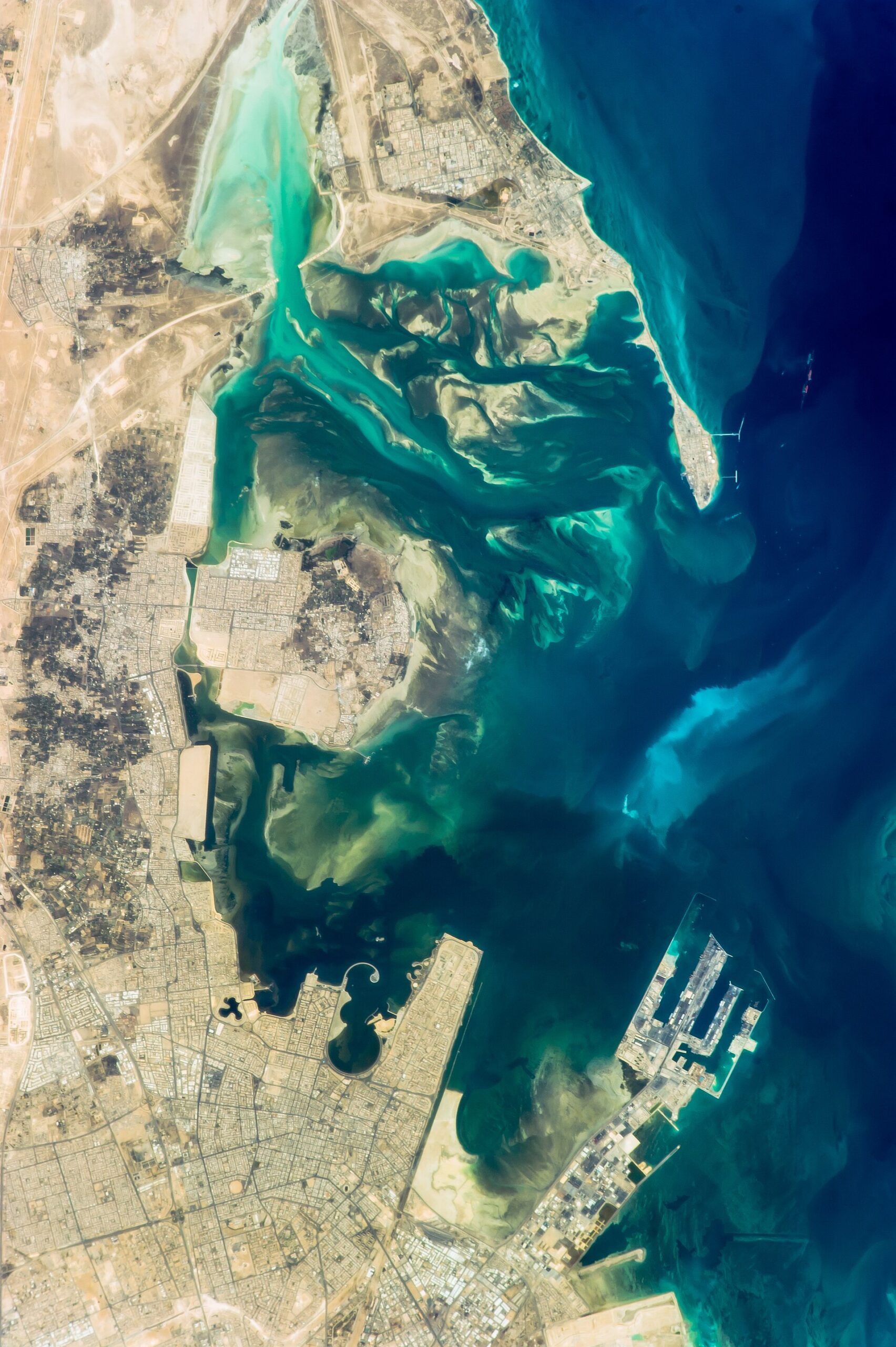 ISS photograph of Tarout Bay, Saudi Arabia, showing Ras Tanura oil terminal peninsula and tanker berths from orbit. Photo: NASA / Public Domain