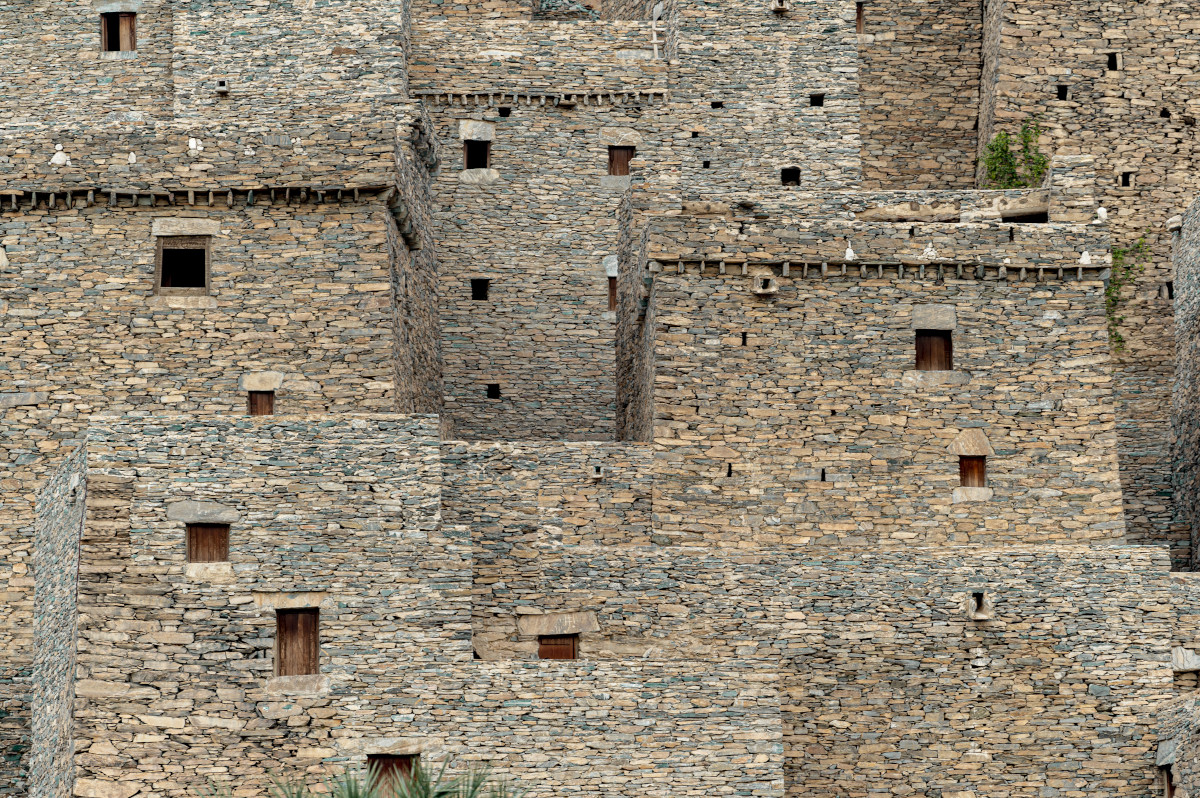 Close-up of Thee Ain's multi-storey stone buildings showing volcanic rock walls and small window openings